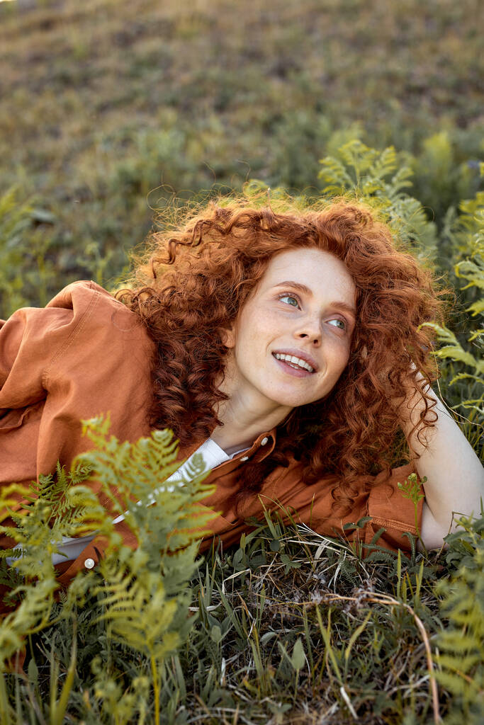 Señora feliz positivo está acostado en la hierba verde en el campo forestal, momento romántico en la naturaleza - Foto, Imagen