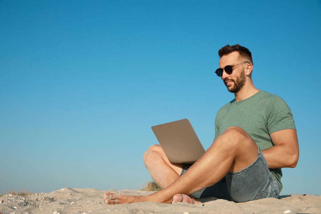 Man working with laptop on beach. Space for text - Photo, Image