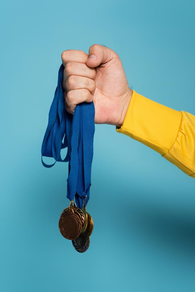 vista ritagliata del campione che tiene medaglie sul blu - Foto, immagini