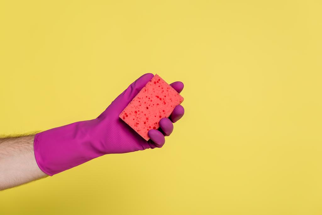 bijgesneden beeld van de mens in roze rubberen handschoen met spons geïsoleerd op geel - Foto, afbeelding