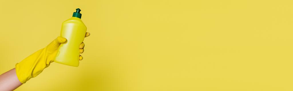 visão parcial do limpador na luva de borracha segurando garrafa com detergente no amarelo, banner - Foto, Imagem