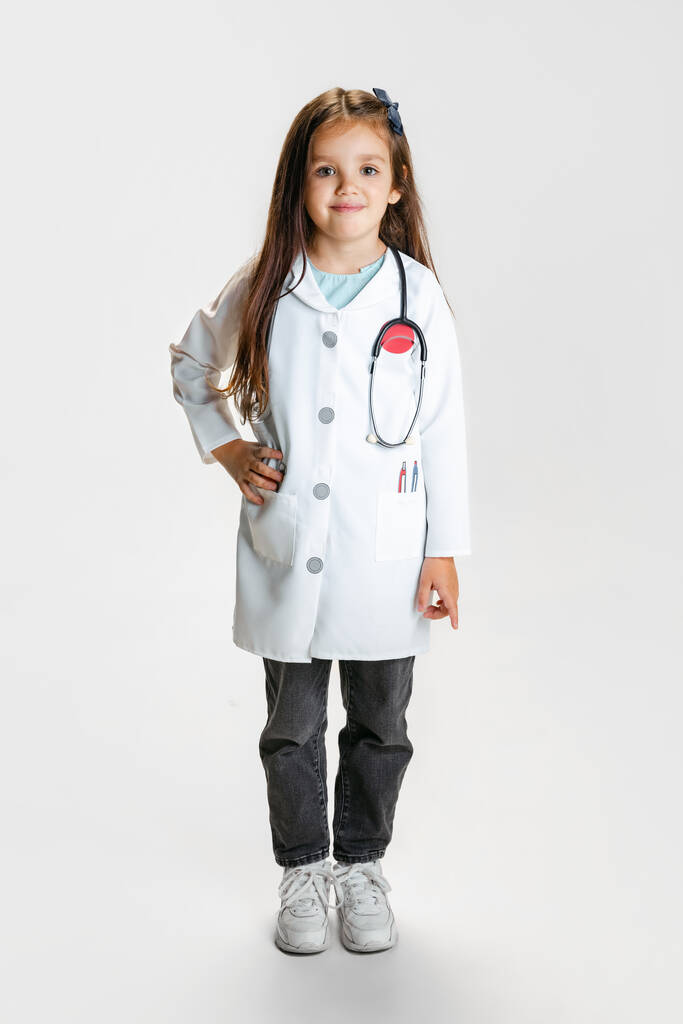 Πλήρες πορτρέτο του χαριτωμένο όμορφο κοριτσάκι, παιδί κατ 'εικόνα του γιατρού φορώντας λευκή ρόμπα εργαστηρίου θέτουν απομονωμένο σε λευκό φόντο στούντιο - Φωτογραφία, εικόνα