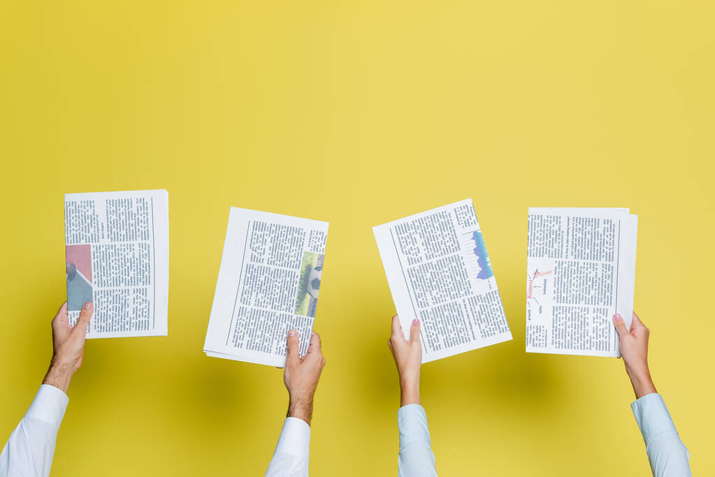 Ausgeschnittene Ansicht von Mann und Frau, die Zeitungen auf gelb halten - Foto, Bild