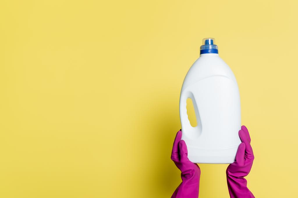 vista parziale di detergente in guanti di gomma bottiglia di tenuta con detergente su giallo - Foto, immagini