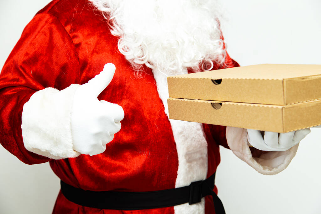 Pizza kutuları Noel Baba 'nın elinde. Noel fast food teslimatı. Yılbaşı gecesi terfisi. - Fotoğraf, Görsel