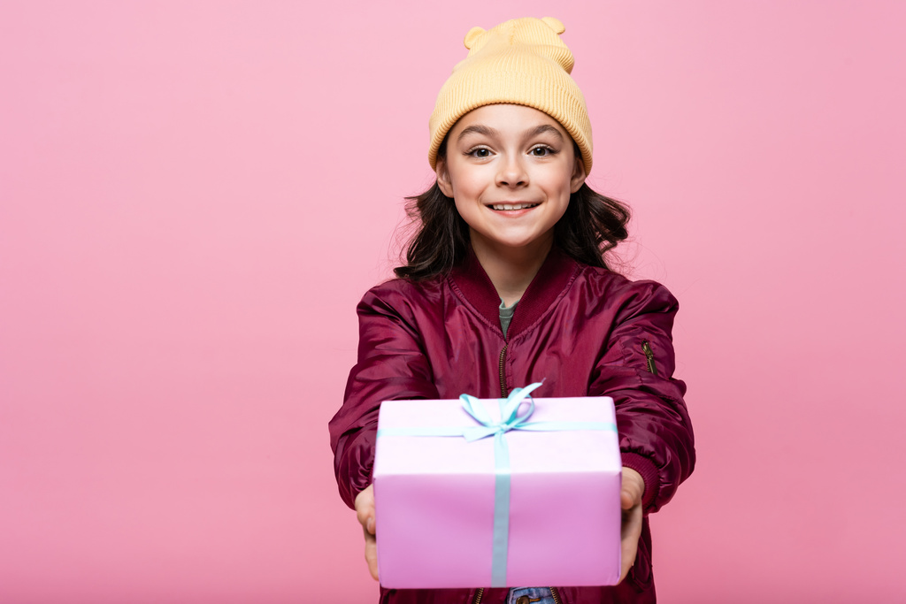 радісна дівчина в модному вбранні тримає загорнутий подарунок ізольовано на рожевому
  - Фото, зображення
