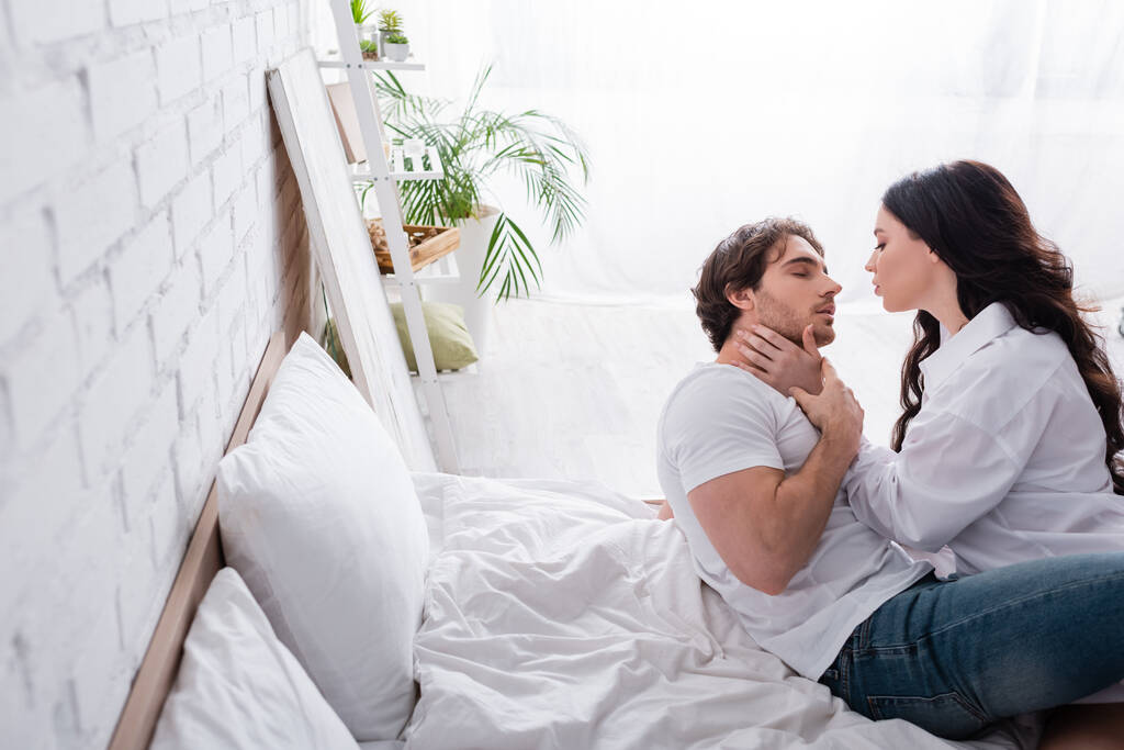 страстная женщина в белой рубашке обнимает парня в спальне - Фото, изображение