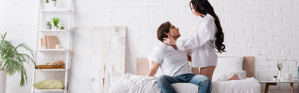 femme passionnée séduire jeune homme assis sur le lit en jeans, bannière - Photo, image