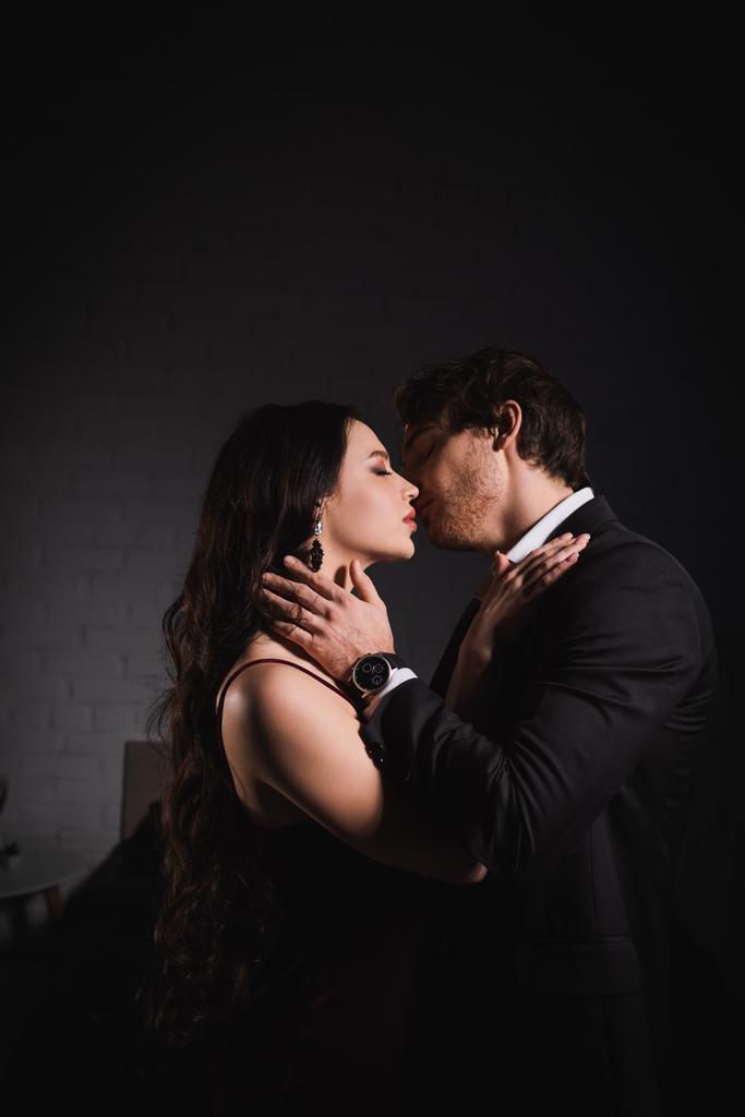 pareja apasionada en ropa elegante besándose por la noche en el dormitorio - Foto, Imagen