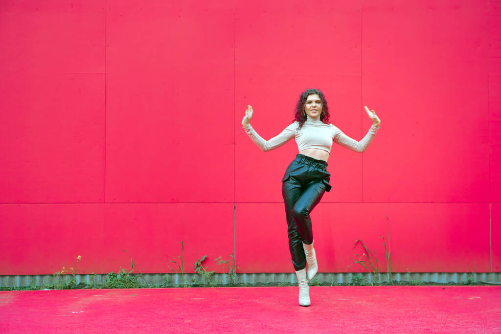 幸せなダンスの女の子は赤い背景、コピースペースの外で現代的なダンスを実行します。女性優雅なダンサークールな動き - 写真・画像