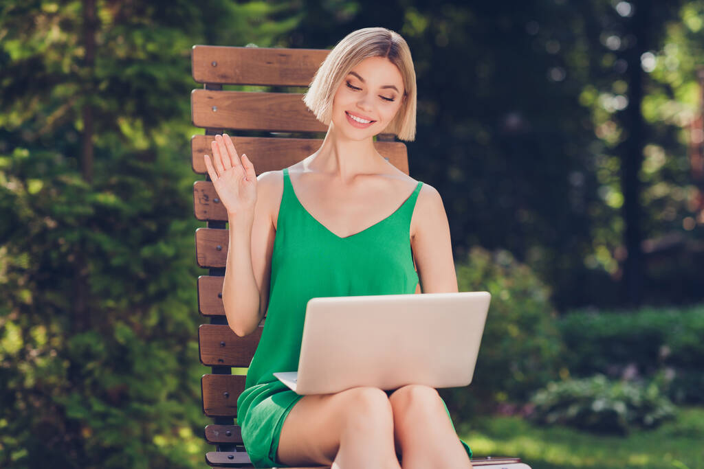 Foto van vriendelijke sociale zakenvrouw houden laptop vergadering op afstand zitten bank dragen groene jurk stedelijke stad buiten - Foto, afbeelding