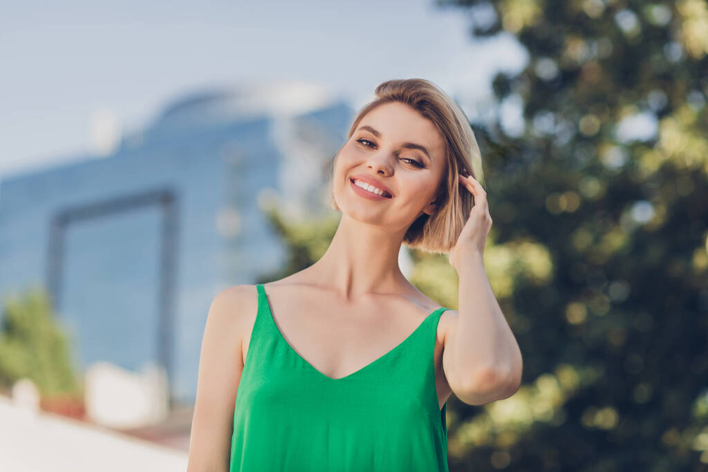 明るい正の素敵な幸せな美しい女性の写真カメラのタッチ髪は外の緑のドレス都市を身に着けている - 写真・画像