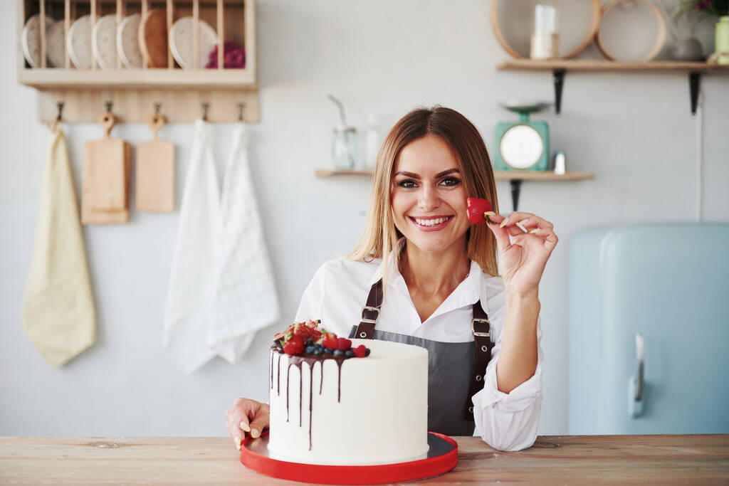 Позитивна блондинка в приміщенні з її домашній пиріг тримає фрукти
. - Фото, зображення