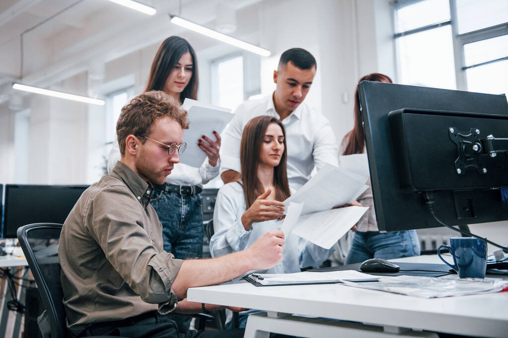 Группа молодых бизнесменов, работающих за компьютерами в современном офисе. - Фото, изображение