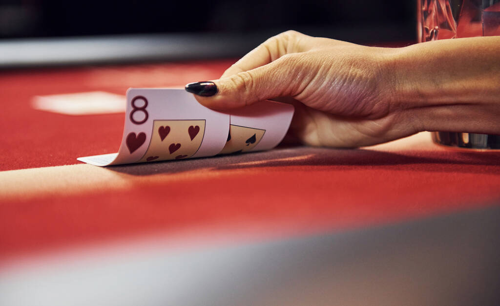 Vista cercana de las manos de la mujer. Chica juega al póquer juego por mesa en el casino y tarjetas de cheques. - Foto, imagen