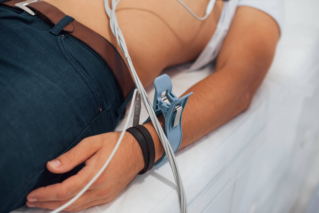 Muž ležící na posteli na klinice a na elektrokardiogramu. - Fotografie, Obrázek