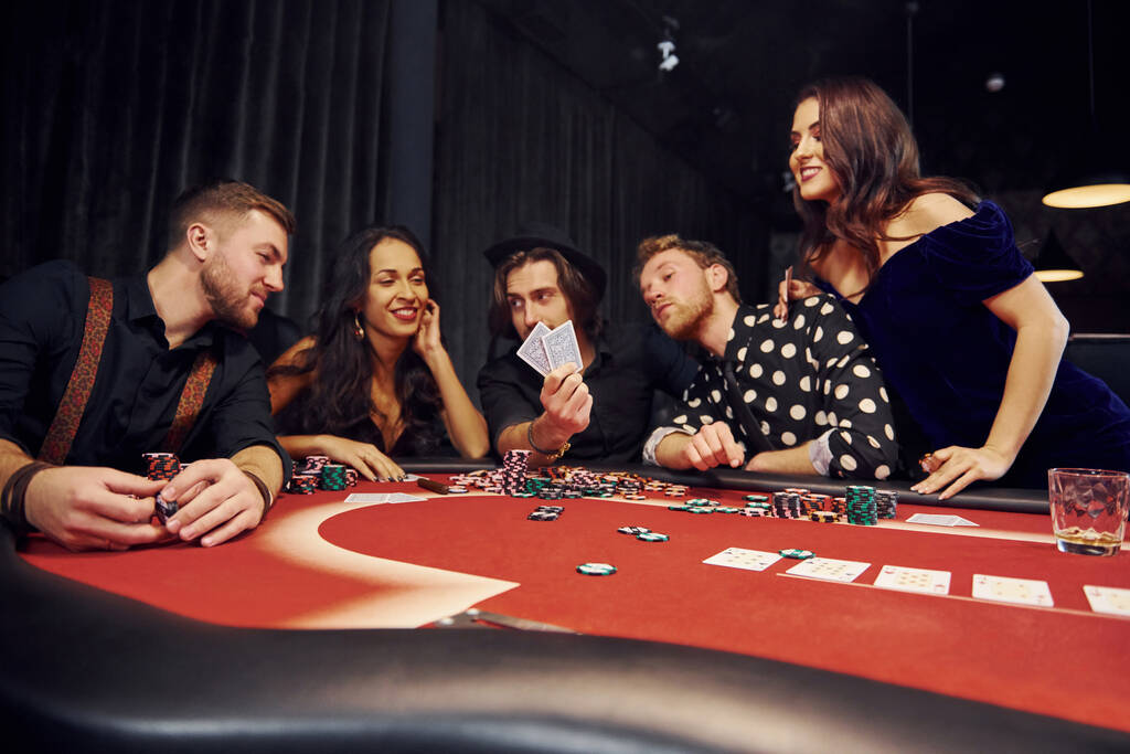 Ryhmä tyylikkäitä nuoria, jotka pelaavat pokeria kasinolla yhdessä. - Valokuva, kuva