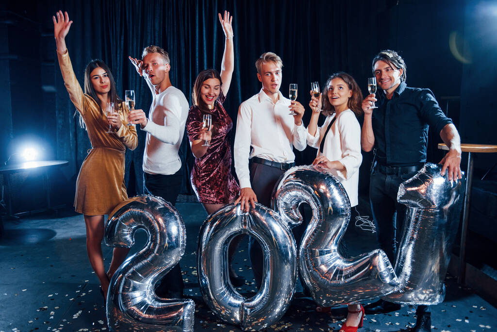 Χαρούμενη ομάδα ανθρώπων με ποτά και μπαλόνια στα χέρια γιορτάζοντας το νέο έτος 2021. - Φωτογραφία, εικόνα