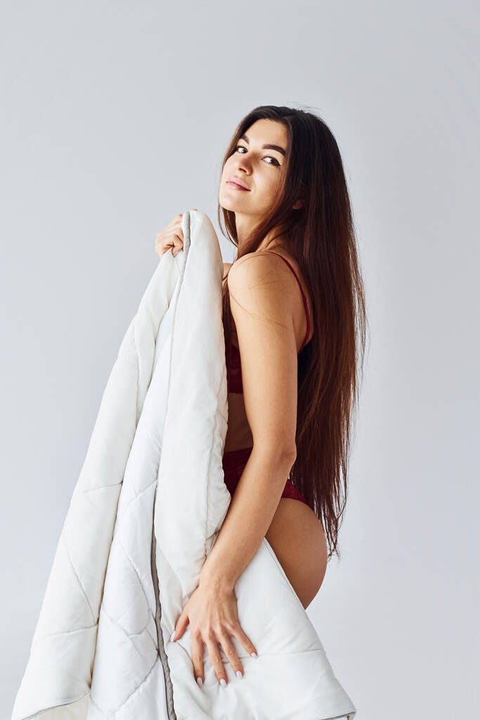 Mujer cubriendo su cuerpo con toalla en el estudio sobre fondo blanco. - Foto, imagen