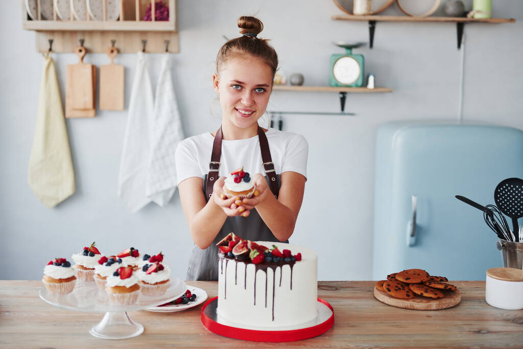 Frau steht mit selbst gebackenem Kuchen in der Küche. - Foto, Bild