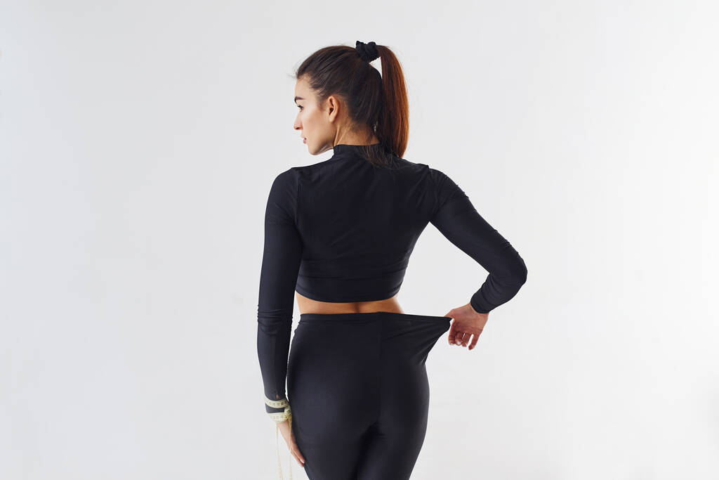 Sportieve vrouw in zwarte kleren in de studio tegen witte achtergrond. - Foto, afbeelding