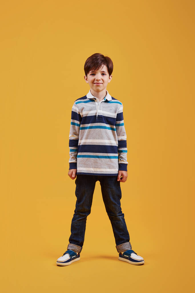 Aranyos kisfiú alkalmi ruhák a stúdióban sárga háttér. - Fotó, kép