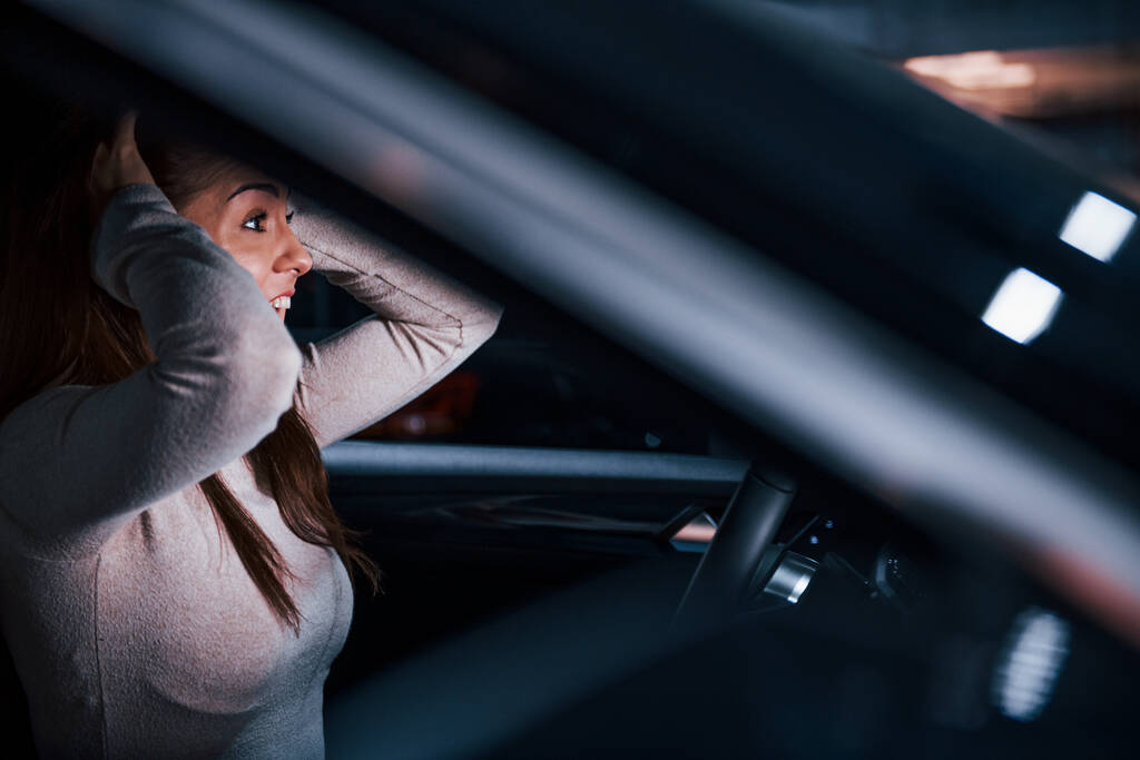 Вид сбоку на молодую женщину, которая жестикулирует внутри совершенно нового современного автомобиля. - Фото, изображение