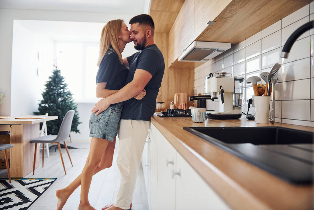 Young couple kissing each other in the kitchen at morning time. - Photo, Image