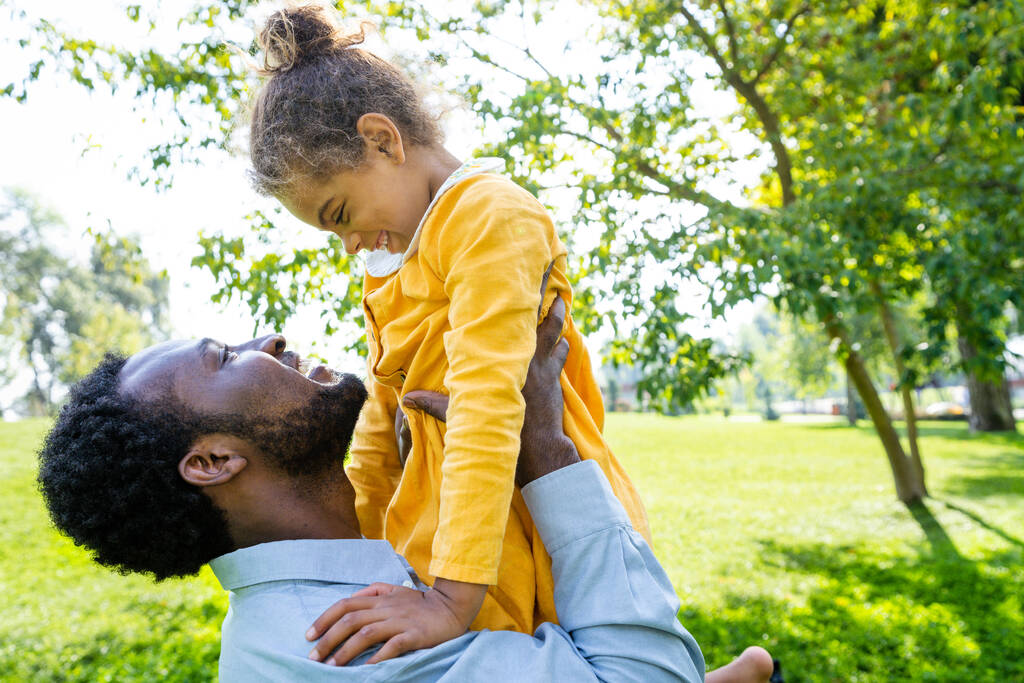 Hermosa familia afroamericana feliz vinculación en el parque - familia negra divirtiéndose al aire libre, papá jugando con su linda hija - Foto, Imagen
