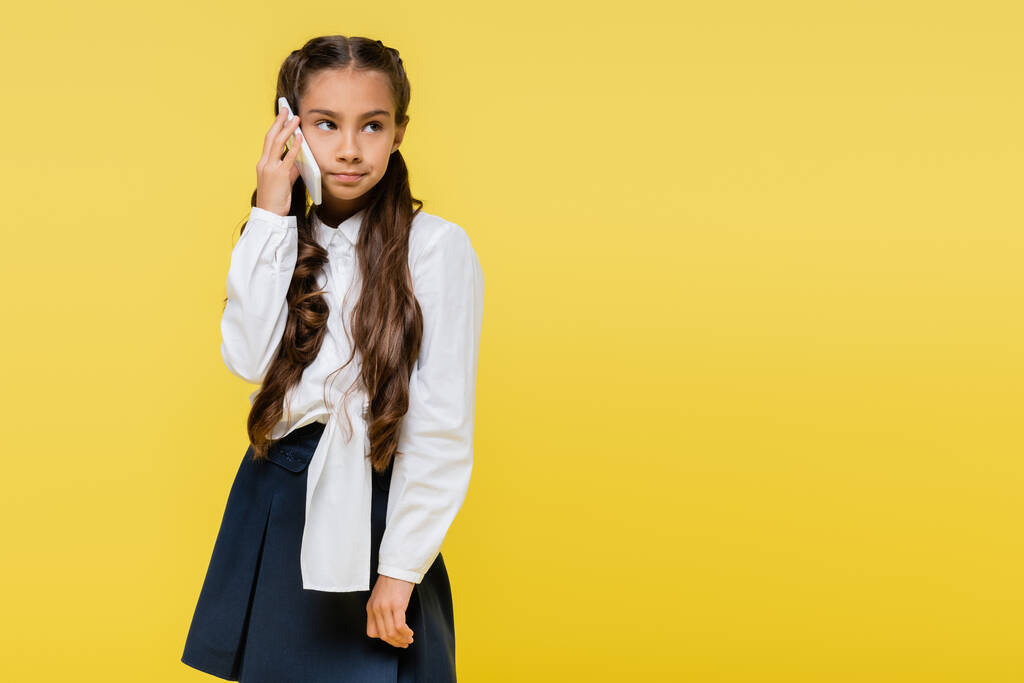 Pensive koulutyttö puhuu matkapuhelimella eristetty keltainen  - Valokuva, kuva