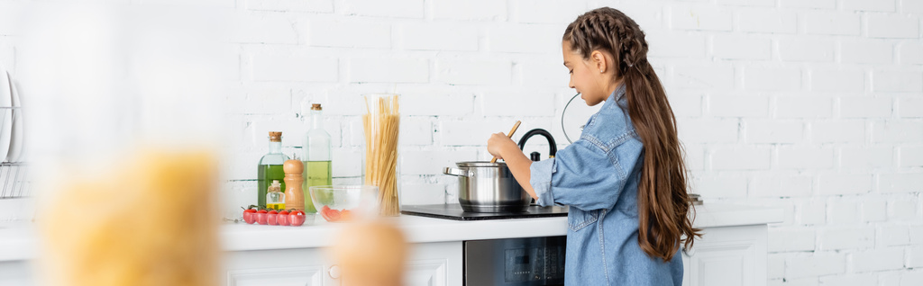 Παιδί μαγείρεμα κοντά σε κατσαρόλα στο φούρνο και τα συστατικά στην κουζίνα, πανό  - Φωτογραφία, εικόνα