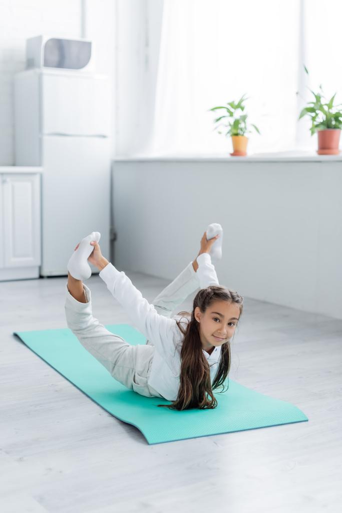 Preteen menina em sportswear treinamento sobre tapete de fitness em casa  - Foto, Imagem
