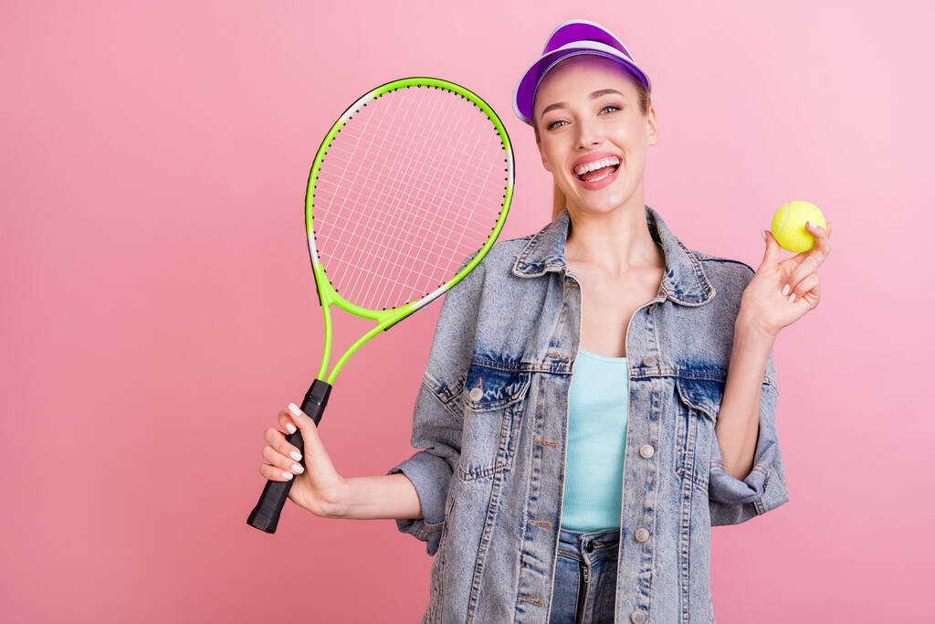 Tenis oynayan neşeli bir kızın portresi. Pembe renkli arka planda izole edilmiş boş zaman geçiriyor.. - Fotoğraf, Görsel