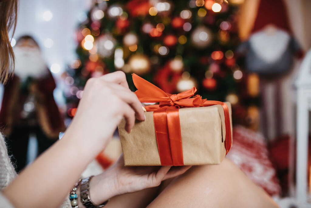 A kezek kezében egy ajándék színes karácsonyfa a háttérben karácsony este - Fotó, kép