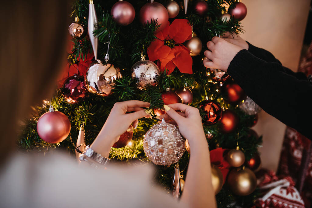 Selektivní snímek mužských a ženských rukou zdobí vánoční stromek - Fotografie, Obrázek