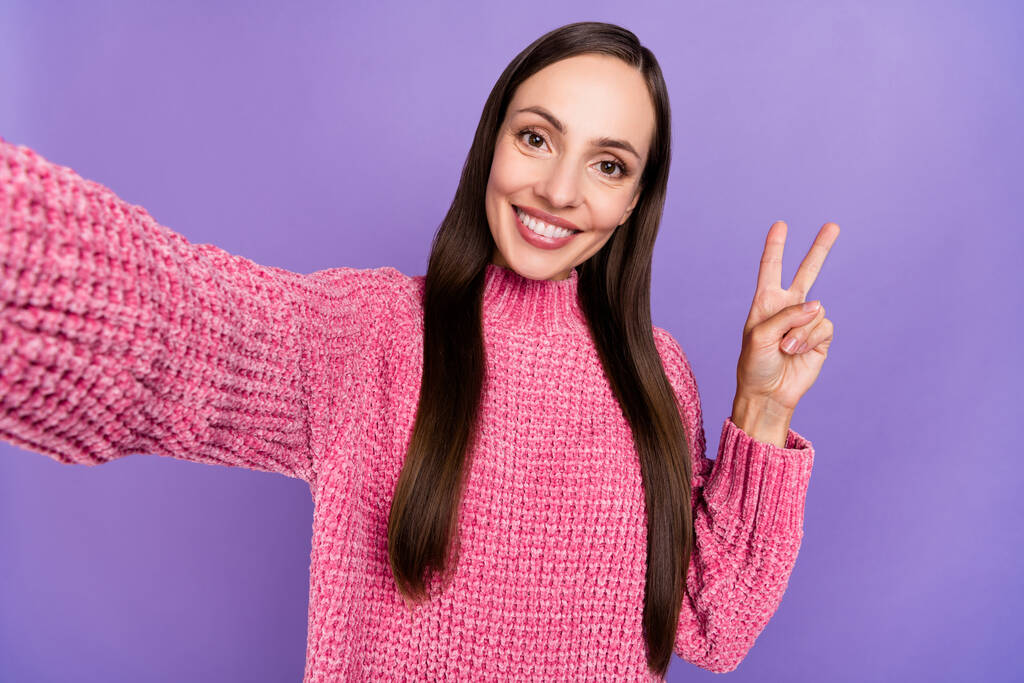 Fotografie cool mladé brunetky dáma do selfie show v-sign oblečení růžový jumper izolované na fialové barvy pozadí. - Fotografie, Obrázek