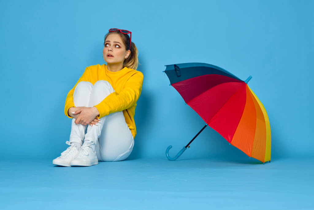 Frau mit buntem Regenschirm in gelbem Pullover posiert in Regenbogenfarben - Foto, Bild