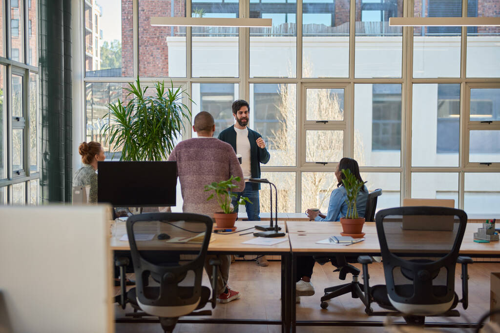 Jungunternehmer unterhält sich bei einem lockeren Treffen in einem modernen Büro mit einer vielfältigen Gruppe von Kollegen bei einem Kaffee - Foto, Bild