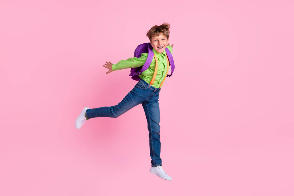 Comprimento total tamanho do corpo vista de belo menino na moda pulando se divertindo isolado sobre cor pastel rosa fundo - Foto, Imagem