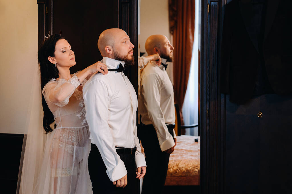 Наречена в будуарній білизні одягається наречений в інтер'єрі готелю
. - Фото, зображення
