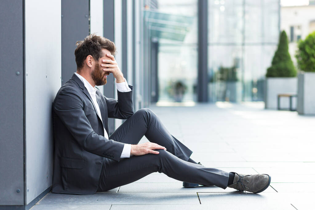 Επιχειρηματίας αποτυγχάνει, απογοητευμένος άνθρωπος κάθεται κοντά στο γραφείο, φτάνει στον ουρανό και ζητά βοήθεια - Φωτογραφία, εικόνα