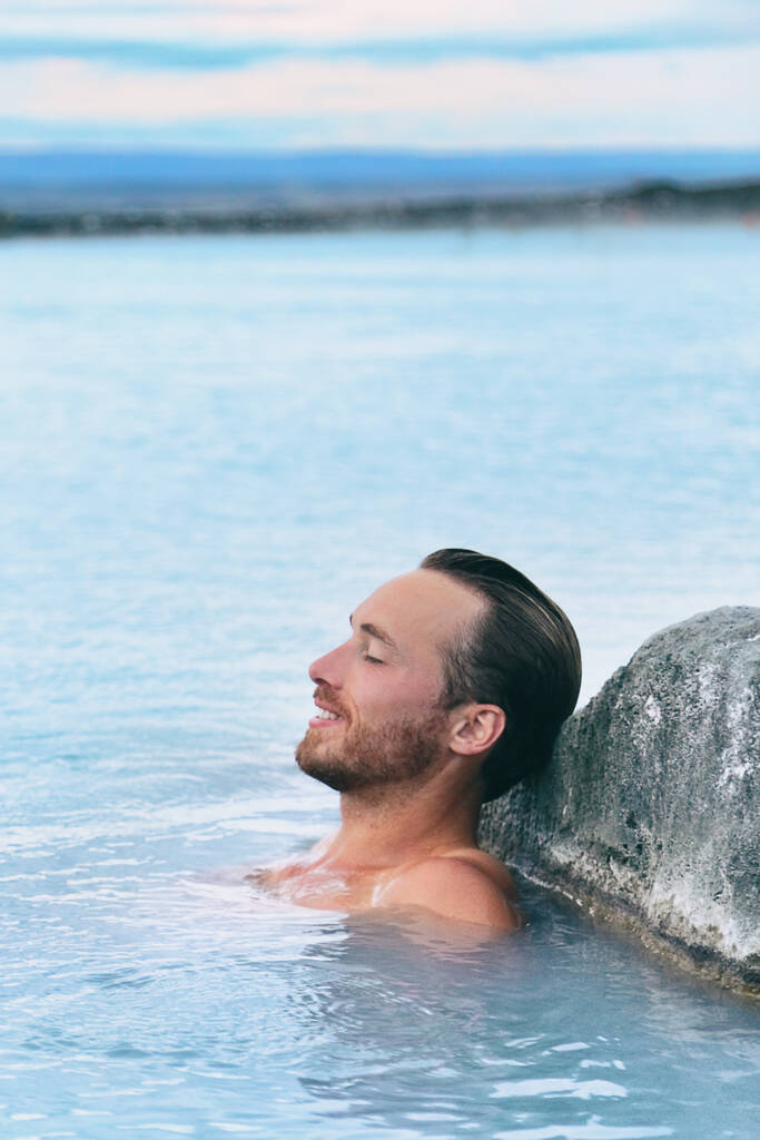 Wellness spa hombre guapo relajante disfrutando de aguas termales geotermales naturales en la naturaleza Islandia al aire libre. Reykjavik turista viajes nórdicos. - Foto, Imagen