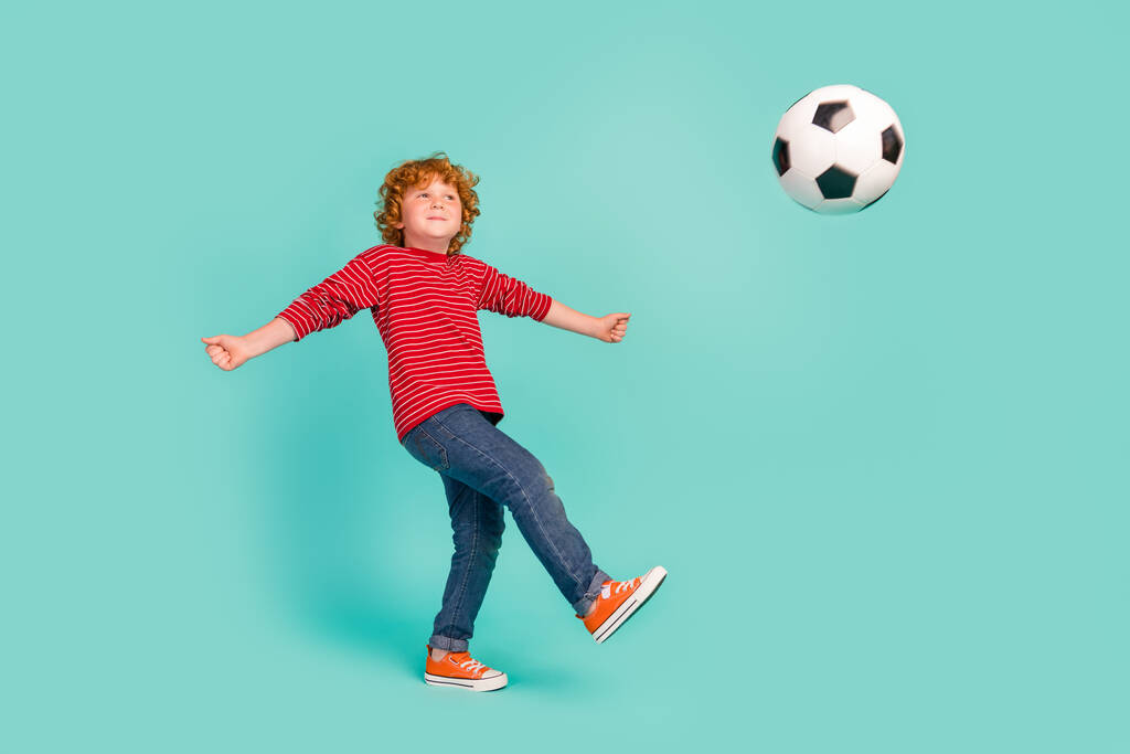 Ganzes Foto von lustigen kleinen Jungen spielen Fußball tragen Hemd Jeans Turnschuhe isoliert auf blauem Hintergrund - Foto, Bild