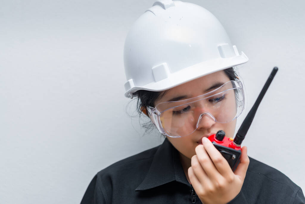 irritado ásia engenheiro mulher vestindo óculos, usando rádio comunicação no fundo branco, tailandês técnico uso walkie talkie para o trabalho
 - Foto, Imagem