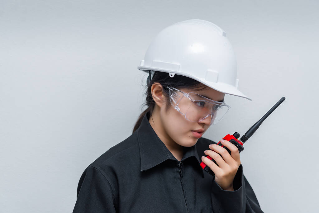 Θυμωμένος Ασιάτης μηχανικός γυναίκα φορώντας γυαλιά, χρησιμοποιώντας ραδιοεπικοινωνία σε λευκό φόντο, Ταϊλάνδη τεχνικός χρησιμοποιούν walkie talkie για την εργασία - Φωτογραφία, εικόνα