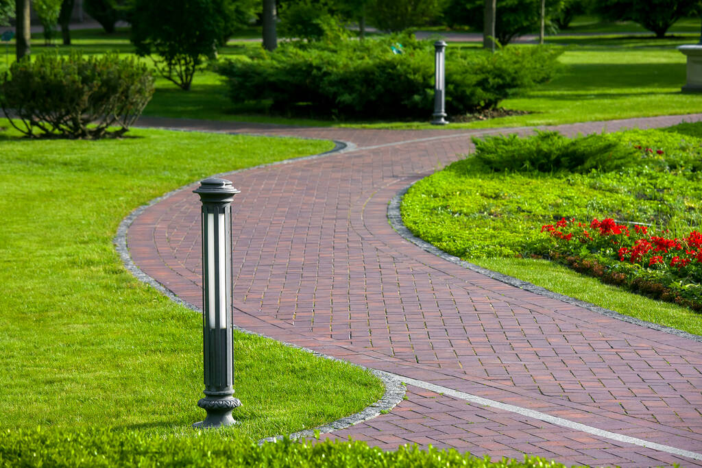 lantern iron ground garden lighting of a park path paved with stone tiles in the backyard among plants, bushes and trees surrounded by a green lawn on a sunny summer day, nobody. - Photo, Image