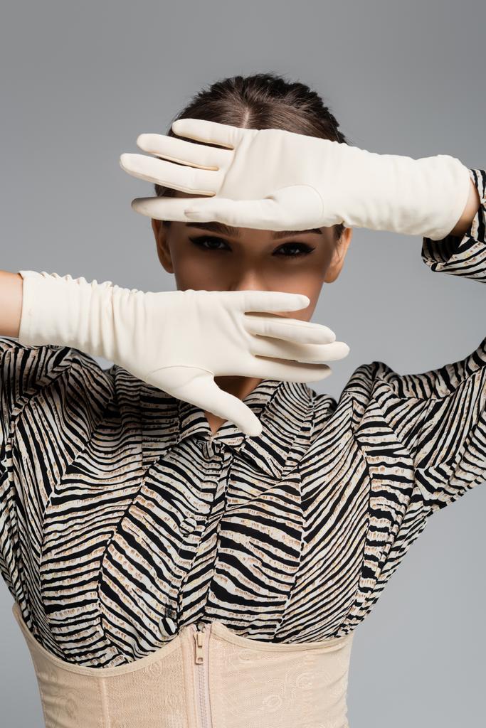 stylische Frau in Bluse mit Zebra-Print und weißen Handschuhen posiert isoliert auf grau - Foto, Bild