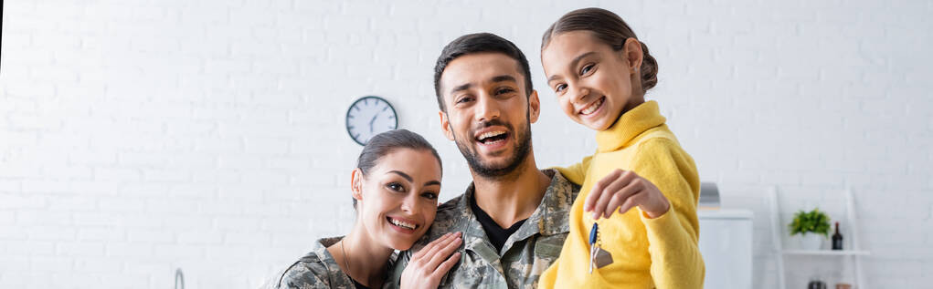 Glückliche Familie in Militäruniform hält Tochter mit Schlüssel zu Hause, Banner  - Foto, Bild