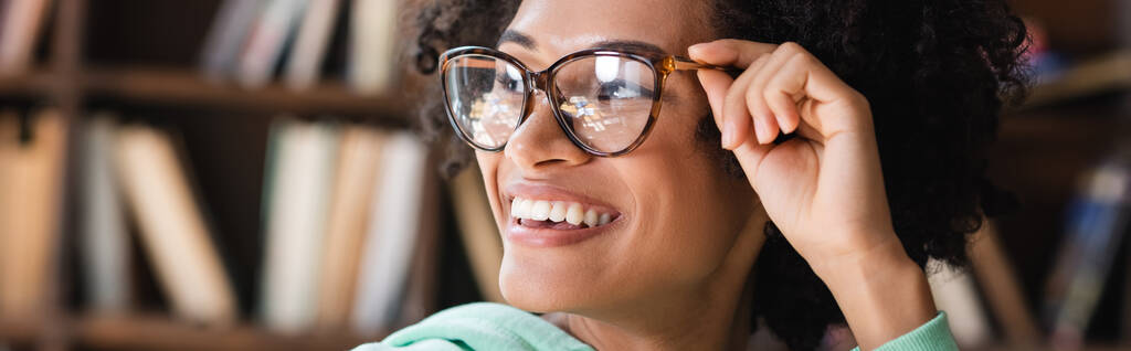 довольный африканский американский студент регулируя очки и глядя в сторону, баннер - Фото, изображение