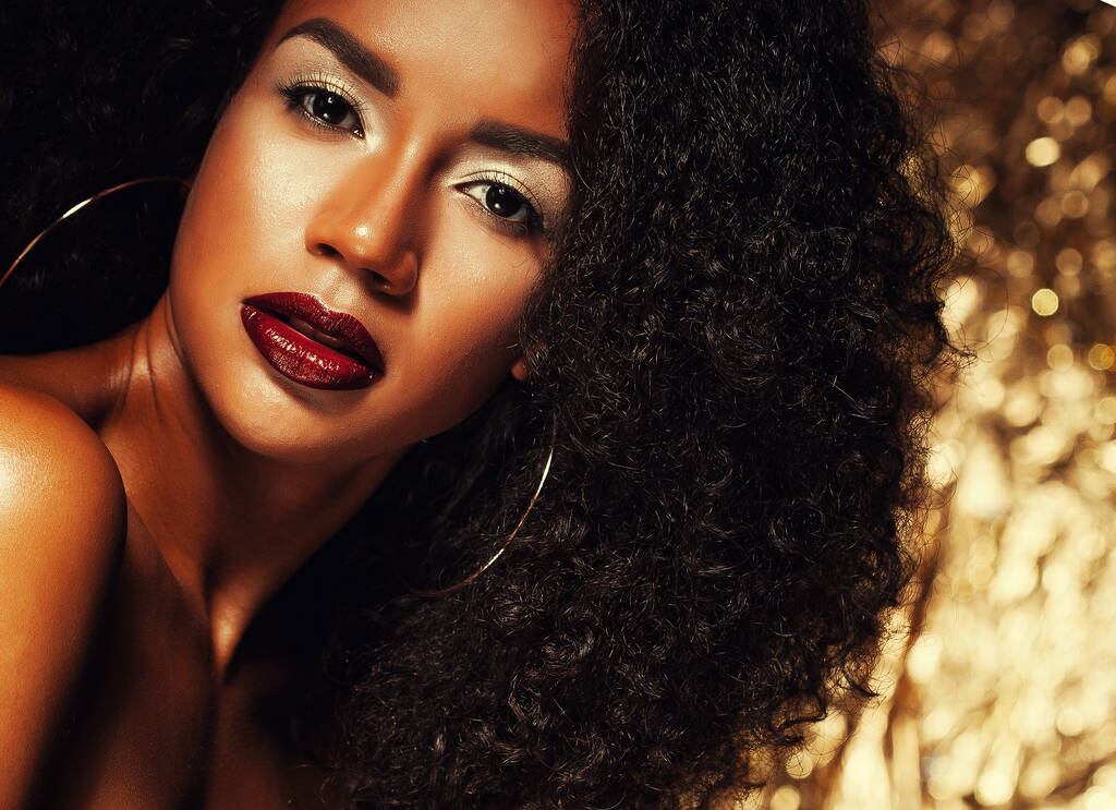 Jonge mooie Afro-Amerikaanse vrouw met afro haar. Glamour make-up. Gouden achtergrond. - Foto, afbeelding